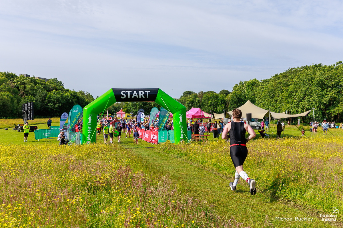 A Tribesman athlete crossing the finish line beneath the arch